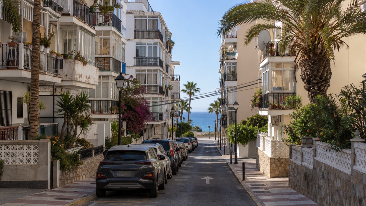Older apartment blocks with glazed balconies on a narrow street at Torrenueva